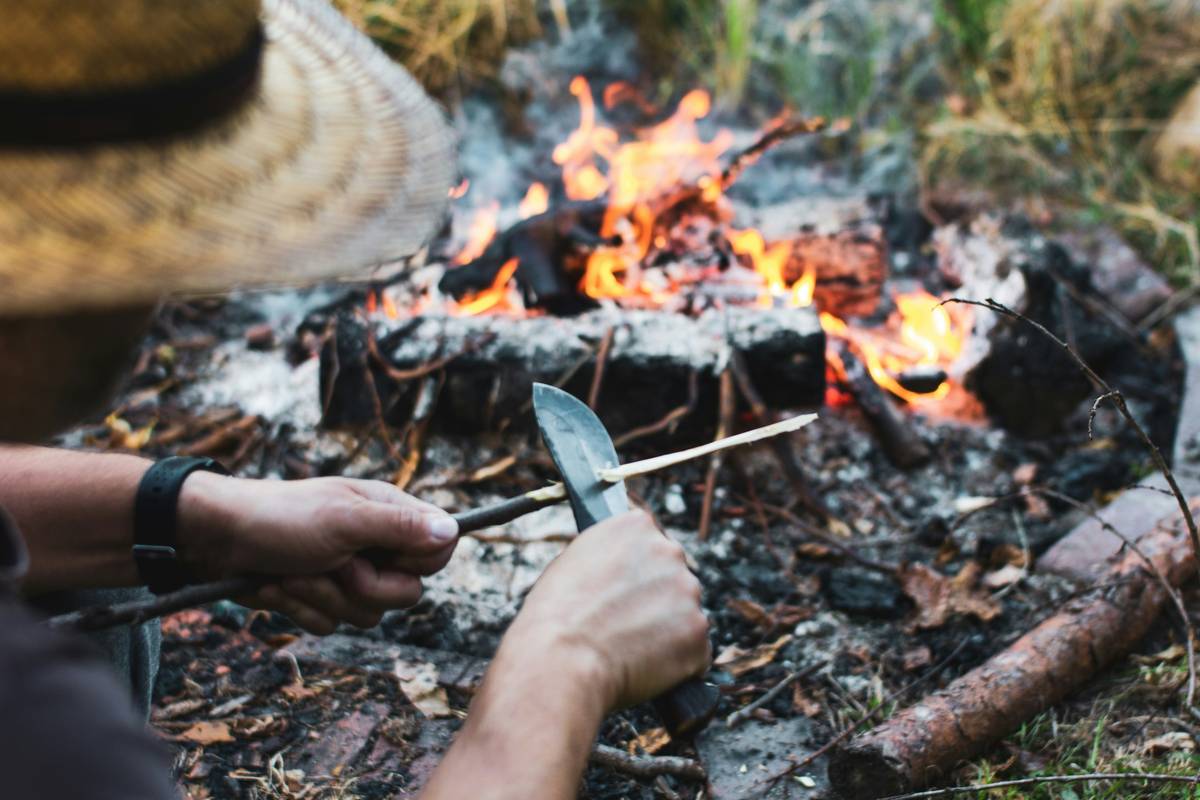 camper practicing camping survival skills by building a shelter in the woods