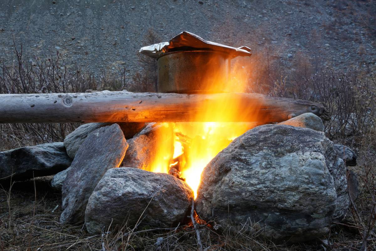 A campfire with a pot on a metal bar